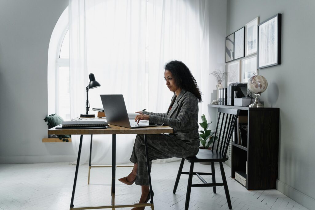 Businesswoman using a laptop at a stylish desk, focused on work in a modern office environment.